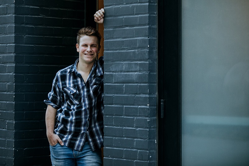 Tạo dáng đặt tay lên tường, tay còn cho vào túi quần